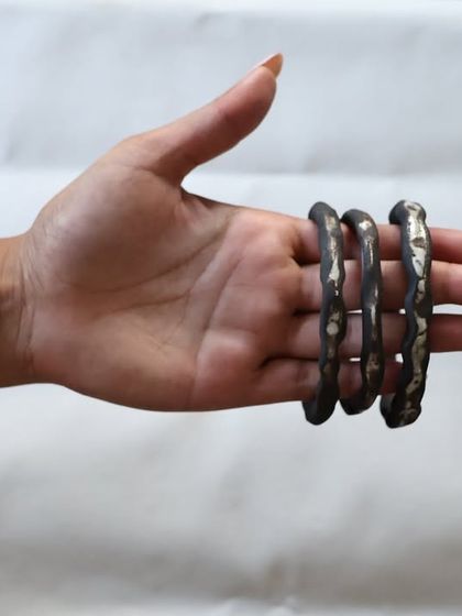 Holding a set of four handmade ceramic bangles. The imperfect, organic shapes are what make them so special and unique.