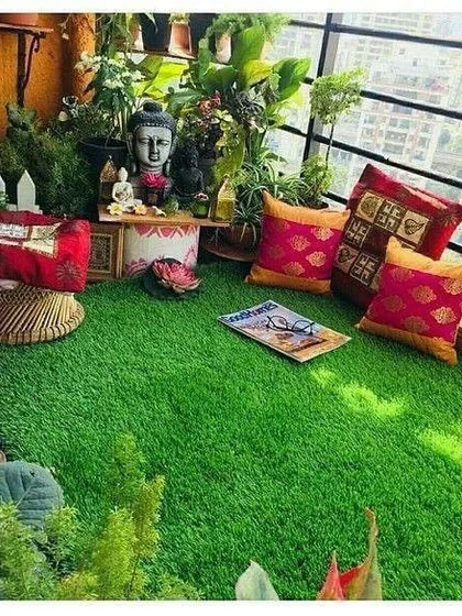 An example of a meditation or relaxation corner on a balcony, using artificial grass for a soft floor, a low seating arrangement with ethnic cushions, and a small altar with a Buddha statue.