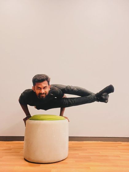 A twisted arm balance, Parsva Bakasana, on an ottoman. This requires deep core rotation and upper body strength.