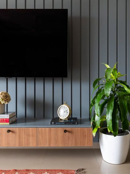 A detail shot of the modern grey TV unit, showing the clean lines of the console and the texture of the vertically paneled wall.
