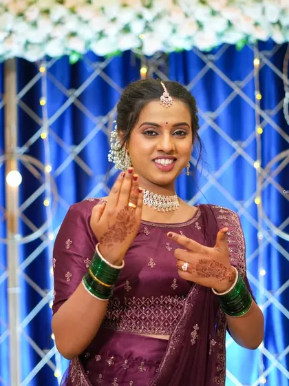 A classic bridal portrait is a must. This shot focuses on the bride looking directly at the camera, showcasing her happiness, intricate jewelry, henna-adorned hands, and wedding attire.