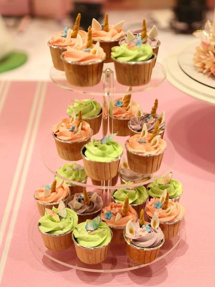 A close-up of the unicorn cupcakes from the "Wonderland" party. Each one is topped with pastel frosting and a tiny, handcrafted unicorn horn and ears, ensuring every single bite fits the magical theme.