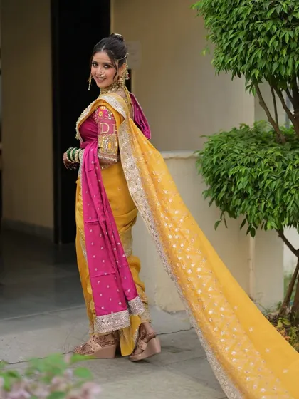 The trail of this bride's saree is as dramatic as it is beautiful. Her makeup is kept soft and elegant to complement the grandeur of her traditional engagement attire.