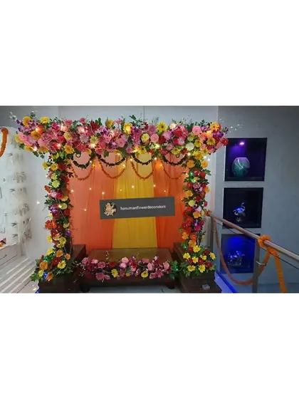 This is a simple stage-style decoration for a home Ganpati celebration. I used a backdrop of orange and yellow drapes with a floral border and fairy lights to create a warm and inviting space for pooja.