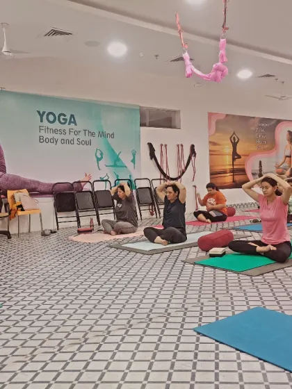 I am leading the class from the front, demonstrating the next posture while students hold a seated meditation pose.