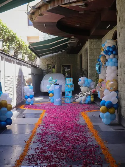 Make a grand statement with a fully decorated driveway and entrance. This welcome home setup includes multiple balloon pillars, a themed backdrop, and a path of flower petals leading to the door, creating a magical welcome.