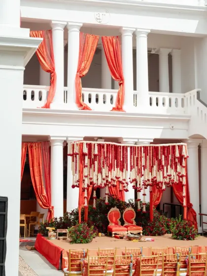 We believe in making a grand first impression. For this wedding, we designed a majestic mandap with cascading strings of red and white flowers, set against the classic architecture of the venue, creating a regal and timeless atmosphere for the ceremony.