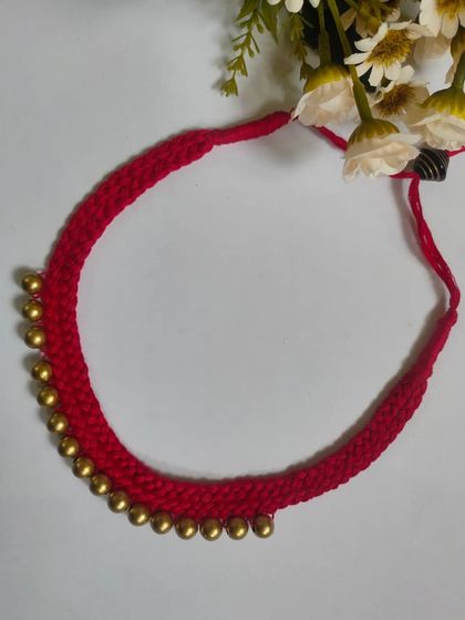 A simple yet beautiful red thread choker with golden ghungroo beads. This handmade necklace is perfect for adding a traditional touch to any outfit.