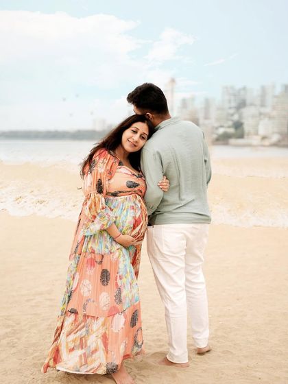 A tender moment on the beach, with the city skyline in the background, blending urban and natural elements.