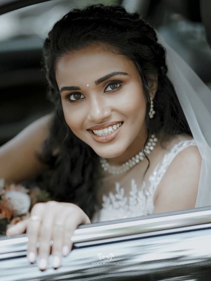 A bright, happy close-up of the bride smiling from her wedding car, her joy absolutely infectious.