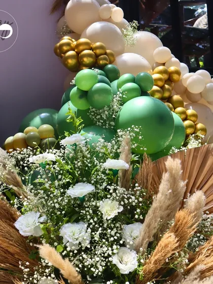 A lush arrangement of green and white balloons, pampas grass, and fresh flowers for a Godh Bharai. This decor combines natural textures with soft colors to create an atmosphere of peace and new beginnings.