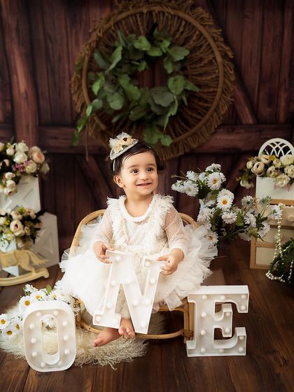 A classic first birthday shot with light-up 'ONE' letters. The soft lighting and rustic decor create a warm and celebratory mood.