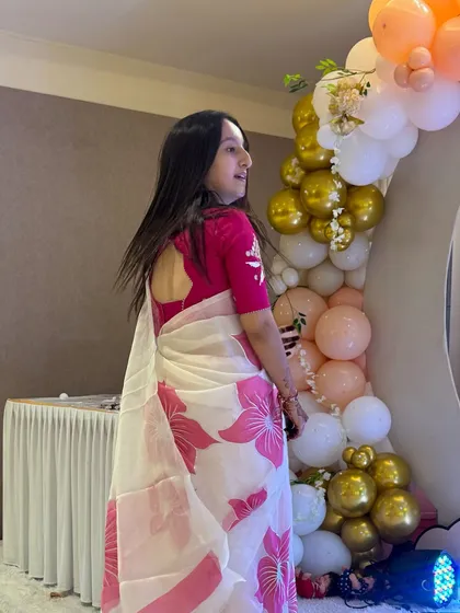 A side profile showing the lovely drape of the saree and the pretty balloon decor at the baby shower.