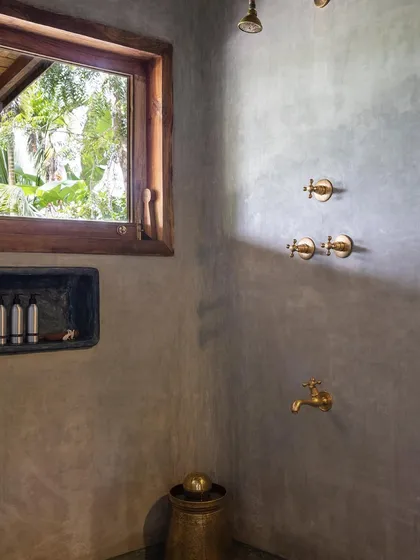 The bathroom of the Garden Suite's green room, where the cement-plastered walls and brass fittings create a warm, earthy aesthetic.