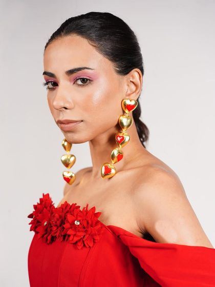 A close-up on accessory styling, featuring dramatic gold and red heart-shaped earrings. This shot shows my attention to detail in selecting jewelry that elevates the entire outfit.