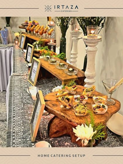 A rustic-chic home catering setup using natural wood risers and a patterned rug to create a warm, inviting, and stylish appetizer station.