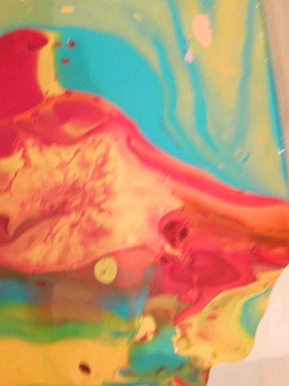 The paint begins to flow across the canvas, with vibrant shades of turquoise, yellow, and red blending together to form a dynamic, flowing landscape.