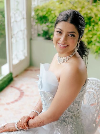 This bride looks ethereal in her white gown. The makeup is soft and glamorous, with a focus on glowing skin and defined eyes, proving that white can be just as bridal as red.