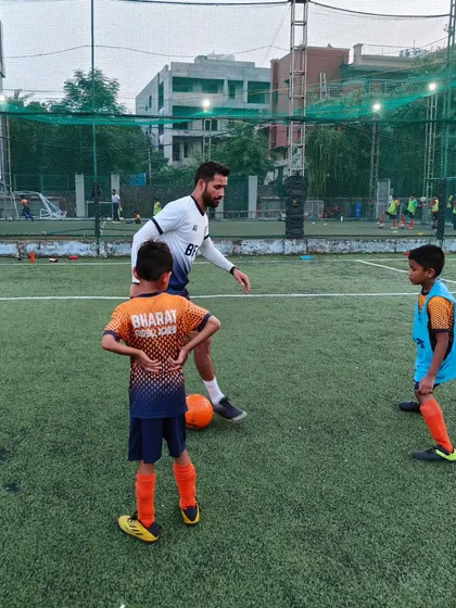 Hands on coaching is central to our philosophy. Here, I am showing two young players the correct body position and technique.