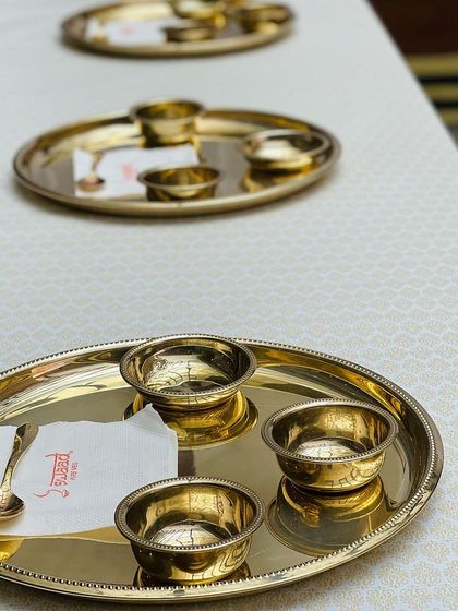 For a more conventional setup, I arrange the Royal Thalis on formally dressed tables. Each place setting includes a gleaming gold thali, matching katoris, and a custom branded napkin.