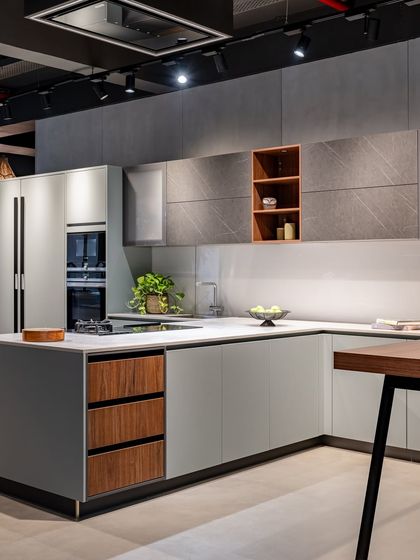 This display in Ahmedabad mixes materials and finishes, combining light grey cabinets with wood-accented drawers and a textured stone-look upper cabinet.