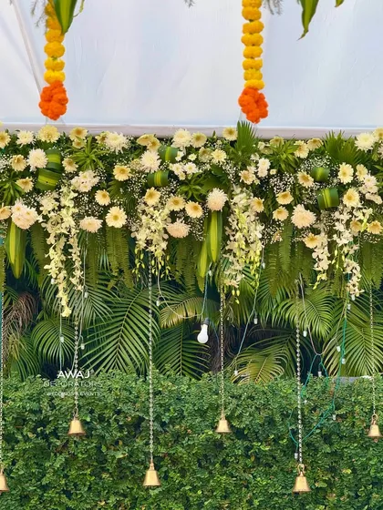 A close-up of the beautiful floral valance of the mandap, with fresh white and yellow flowers and hanging bells.