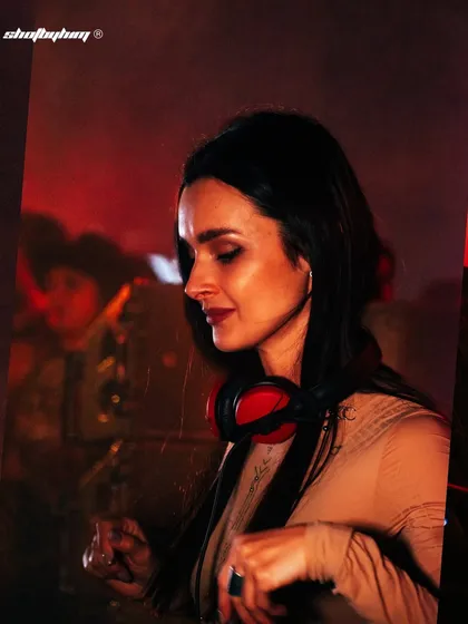 A serene profile of DJ Korolova at Zamna India, bathed in soft red light. This close-up captures the focus and emotion of a DJ in the zone, telling a story beyond just the spectacle.