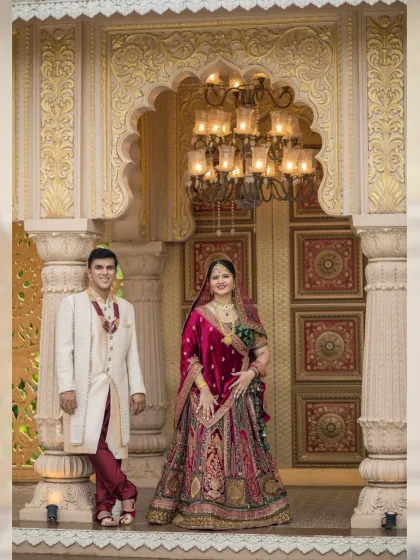 Framed by an ornate golden archway, the couple stands as a picture of elegance. This shot highlights the stunning details of both their attire and the palatial location.
