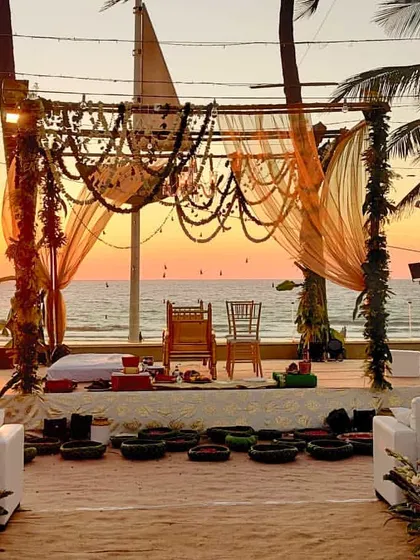 A perfect example of a rustic and bohemian beach wedding. We designed this mandap using natural wood, draped fabrics, and traditional Indian beaded garlands, all set against a stunning sunset over the water.