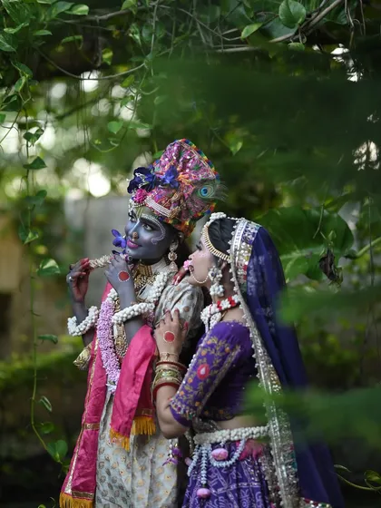 An intimate shot of Radha and Krishna in a lush, natural setting.