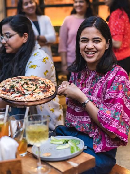 The pure joy of pizza arriving at the table. A customer's happy smile says it all.
