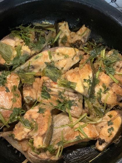 The fish curry after being garnished with fresh herbs.