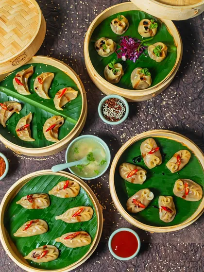 A feast of our handcrafted momos, steamed to perfection in traditional bamboo baskets. This spread shows the variety we offer, each dumpling filled with spiced ingredients and served with our signature clear soup and dipping sauces. This is the heart of Himalayan comfort food.
