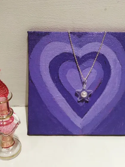 A simple and elegant star shaped pendant with a single pearl embedded in the center.