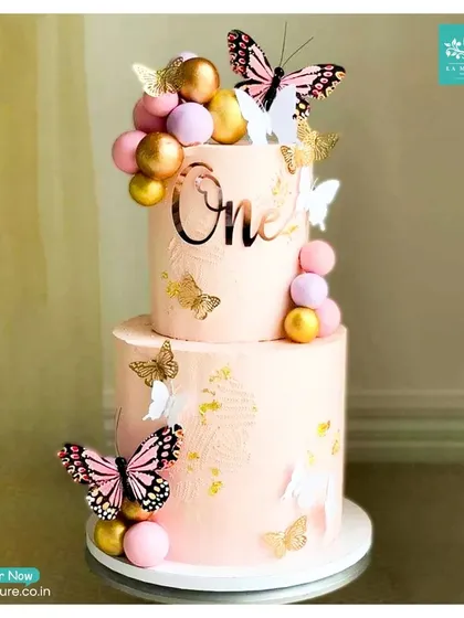 Celebrating a first birthday is a huge milestone, and I can create the perfect themed cake to match. This two-tiered butterfly cake in soft pink is decorated with gold and pink spheres, a custom 'One' topper, and delicate, colourful butterflies.