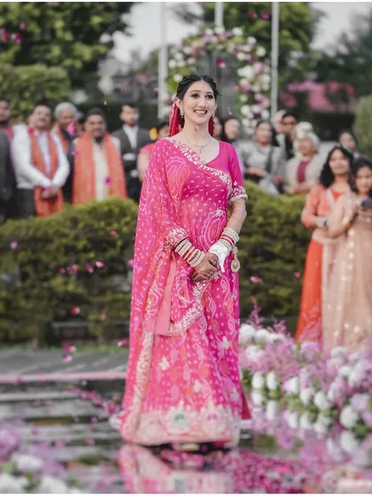 A wide shot of the bride's entrance, showing her walking down an aisle adorned with flowers, surrounded by her loved ones.