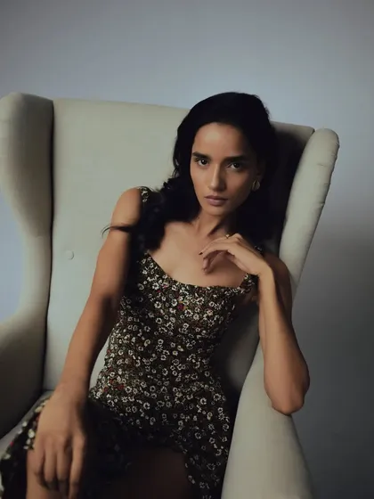 A relaxed pose in a wingback chair. The lighting is soft and the makeup is natural, creating a sophisticated and moody portrait.