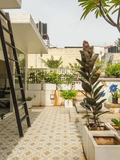 This urban terrace is treated as an outdoor room, complete with potted trees, patterned tile flooring, and curated murals. It's a space designed for light and life, where architecture takes a backseat to the vibrant greenery.