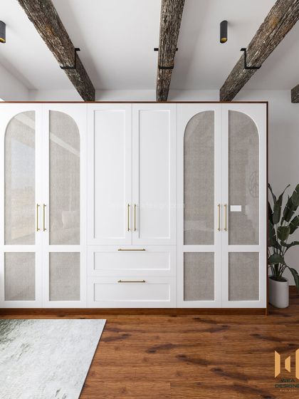 The elegant wardrobe in the rustic bedroom, with white arched doors featuring fabric panels, framed in dark wood.