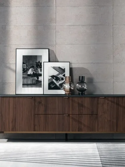 The Fierce sideboard, featuring a compact, rounded structure in striped Canaletto walnut, lightened by a metal base and matching handles.