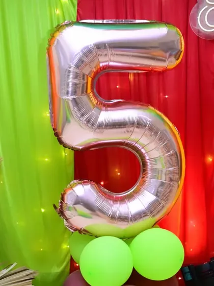 A large number '5' foil balloon, a key element in Vihaan's 5th birthday party decor. We use a variety of balloon types to add dimension and focus to our setups.
