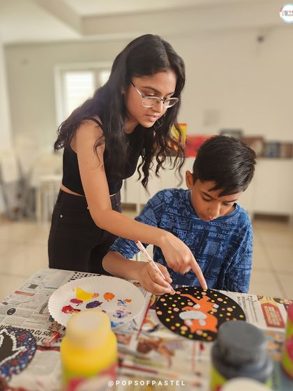 A private dot painting session where a young boy gets one-on-one instruction to create his own coaster designs.
