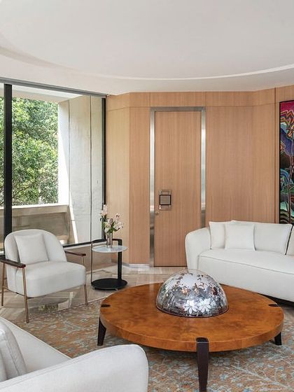 A lounge for directors on the second floor of 'The Layered Office'. The space is bright and airy, with light wood paneling, white furniture, and large windows that look out onto the building's central courtyard.