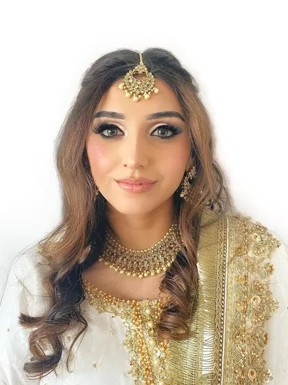 A classic and regal look for a pre-wedding event. The makeup is centered around a defined smokey eye and glowing skin, perfectly paired with traditional gold jewelry and a white and gold outfit.