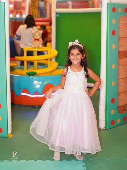 A little princess poses in front of our vibrant soft play area. Even in her beautiful party dress, she's ready to jump into the fun and explore our exciting play structures.