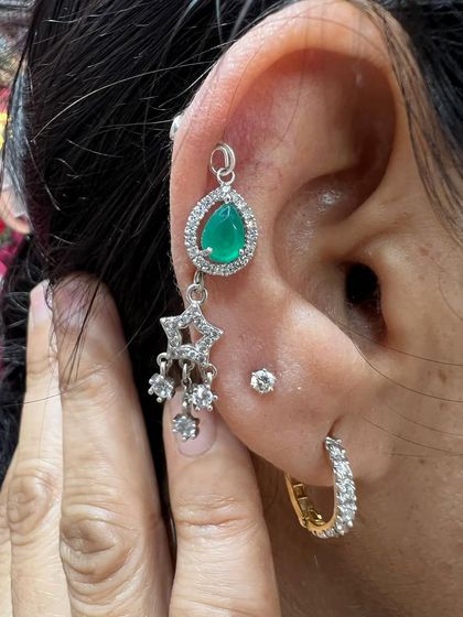 A statement hanging with a large green stone and star-shaped drops, paired with a simple hoop.