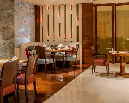 A cozy dining nook at Tamari, featuring custom wall lighting and a mix of upholstered chairs. The space is designed to feel both modern and traditional, with layers of texture and warm tones.