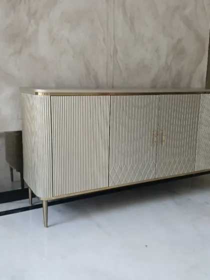This metallic finish buffet console is a testament to modern elegance. We designed it with clean, fluted textures and fine conical steel legs to create a statement piece that offers both significant storage and a sophisticated aesthetic for dining or living areas.