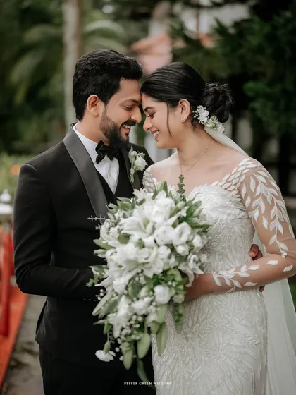 A beautiful close-up of the bride and groom, their heads together, sharing a quiet, happy moment. The intricate details of her dress and the soft bouquet add to the romance.