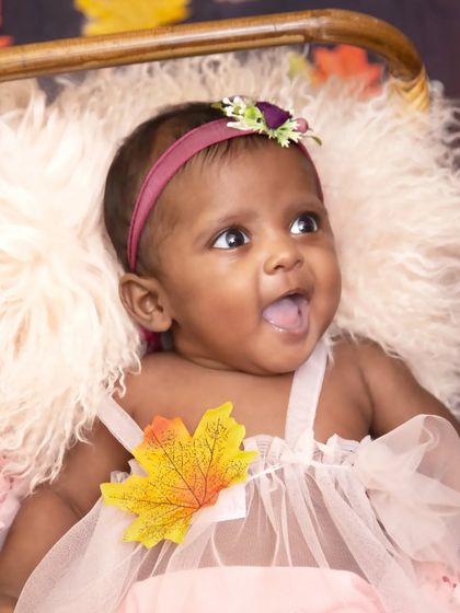 A beautiful close-up capturing a moment of pure joy. This baby girl's happy expression is the highlight of this autumn-themed portrait, showing that every emotion is worth capturing.
